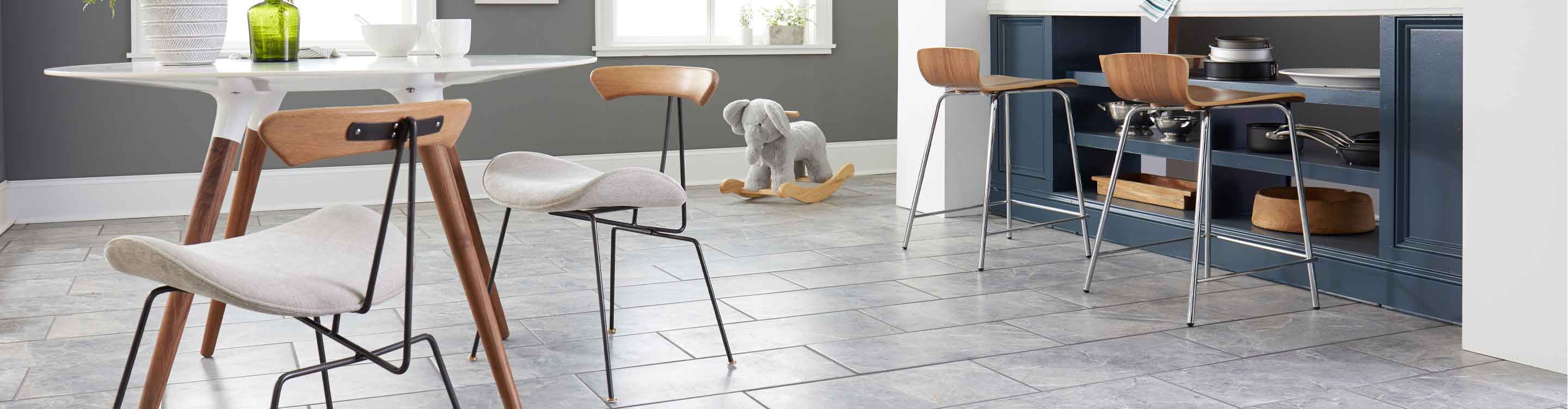 gray marble look tile in modern kitchen with blue island and wooden stools 